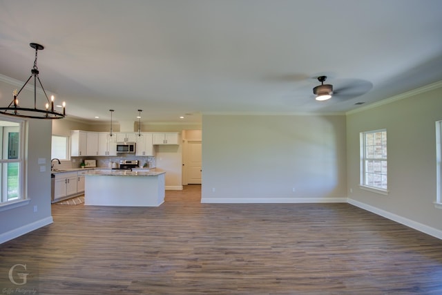 kitchen featuring hanging light fixtures, ornamental molding, appliances with stainless steel finishes, a kitchen island, and white cabinets