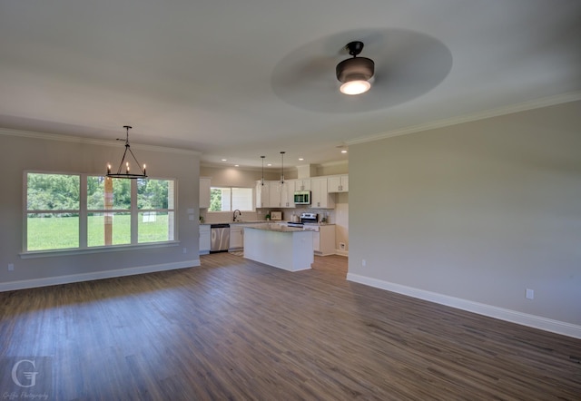 kitchen featuring sink, white cabinetry, decorative light fixtures, appliances with stainless steel finishes, and a kitchen island