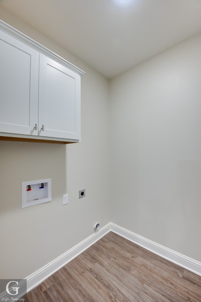 clothes washing area with electric dryer hookup, hookup for a washing machine, light wood-type flooring, and cabinets