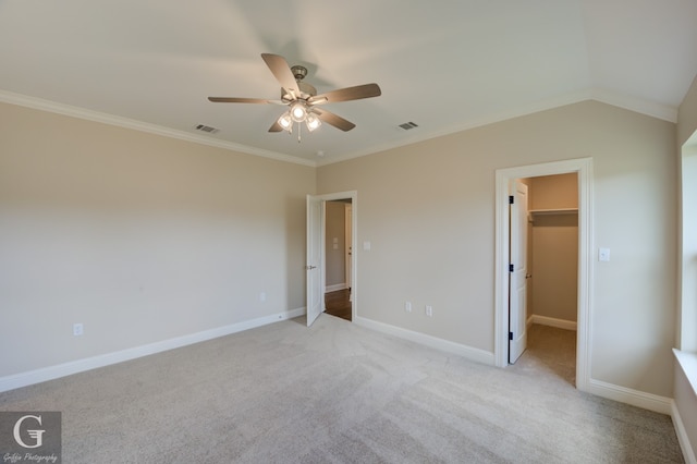 unfurnished bedroom featuring ceiling fan, a spacious closet, ornamental molding, and light carpet