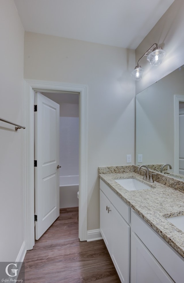 bathroom featuring double sink vanity, hardwood / wood-style flooring, and toilet