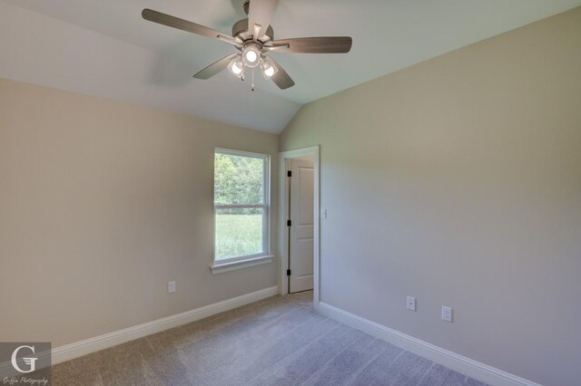 carpeted spare room featuring ceiling fan and vaulted ceiling