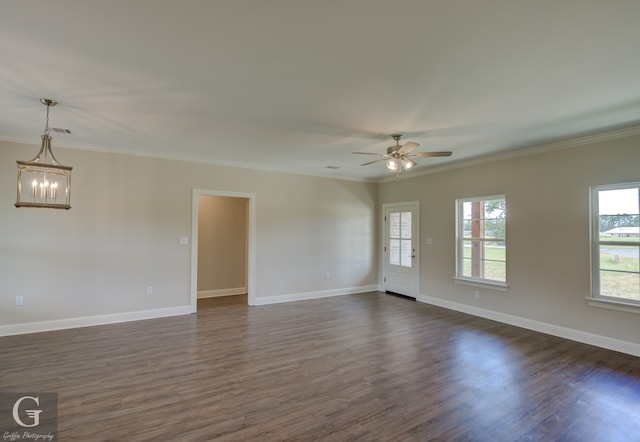 spare room featuring ceiling fan with notable chandelier, dark wood-type flooring, and ornamental molding