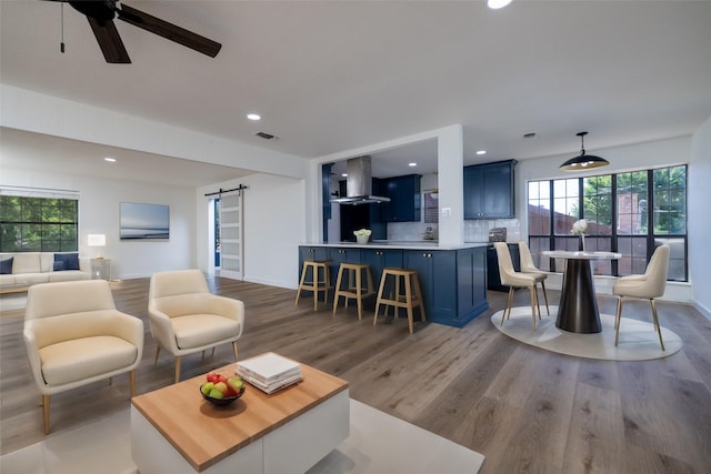 living room featuring a barn door, ceiling fan, and hardwood / wood-style flooring