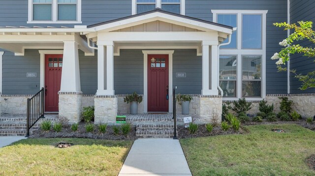 view of exterior entry featuring a yard and covered porch