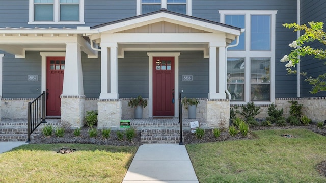 doorway to property with stone siding, covered porch, and board and batten siding