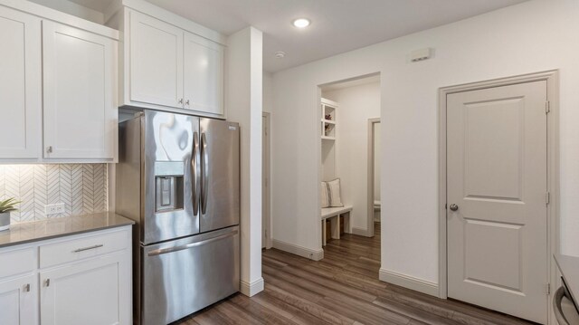 kitchen with white cabinetry, backsplash, stainless steel fridge, and wood-type flooring