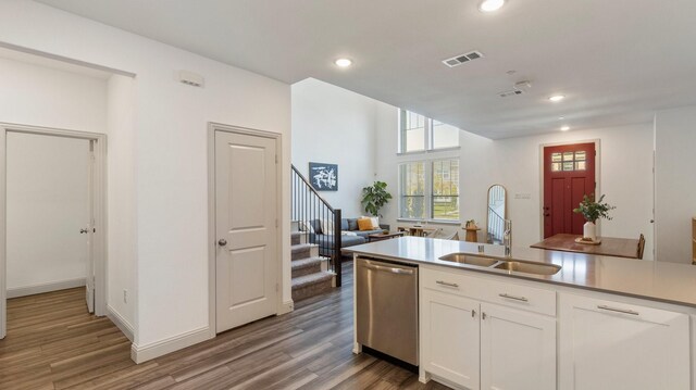 kitchen featuring sink, white cabinets, stainless steel dishwasher, and wood-type flooring