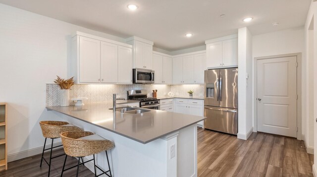 kitchen featuring white cabinetry, appliances with stainless steel finishes, hardwood / wood-style flooring, and kitchen peninsula