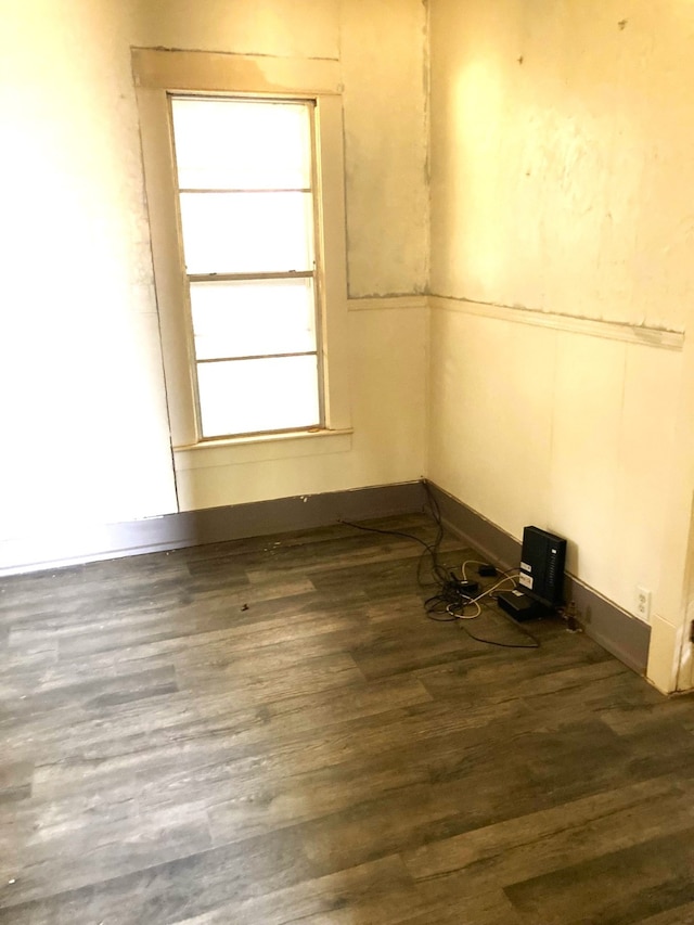 empty room with dark hardwood / wood-style flooring and a healthy amount of sunlight