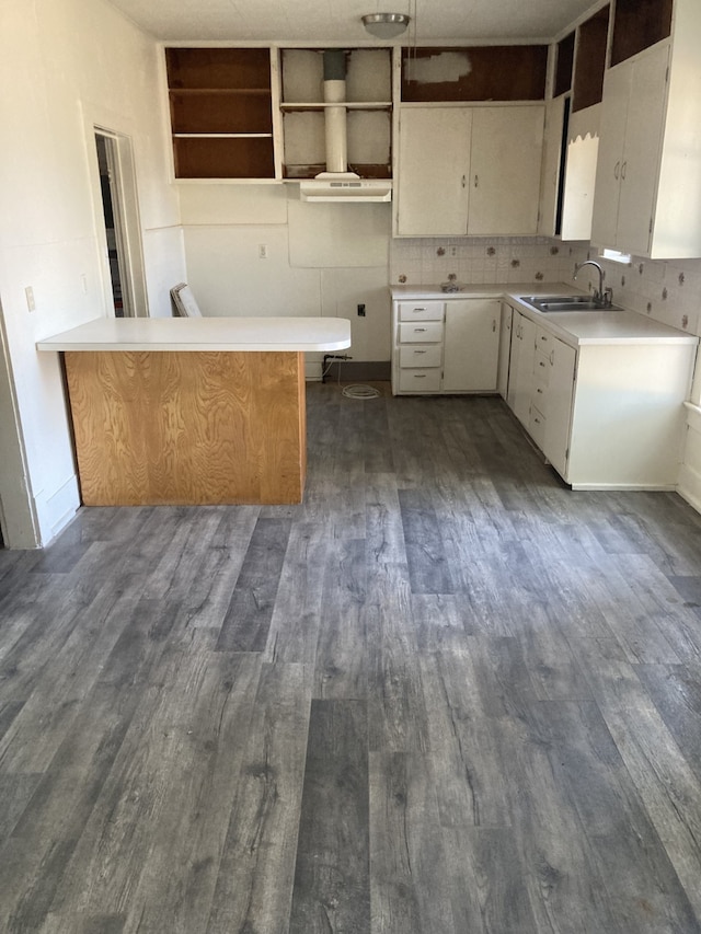 kitchen with dark hardwood / wood-style flooring, sink, white cabinets, decorative backsplash, and kitchen peninsula