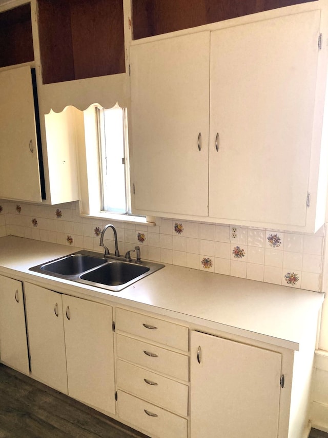 kitchen with dark wood-type flooring, backsplash, sink, and white cabinetry