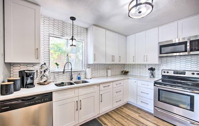 kitchen featuring white cabinets, light hardwood / wood-style floors, appliances with stainless steel finishes, and sink