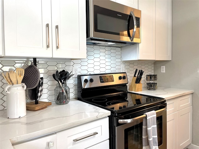 kitchen with light stone counters, stainless steel appliances, backsplash, and white cabinetry