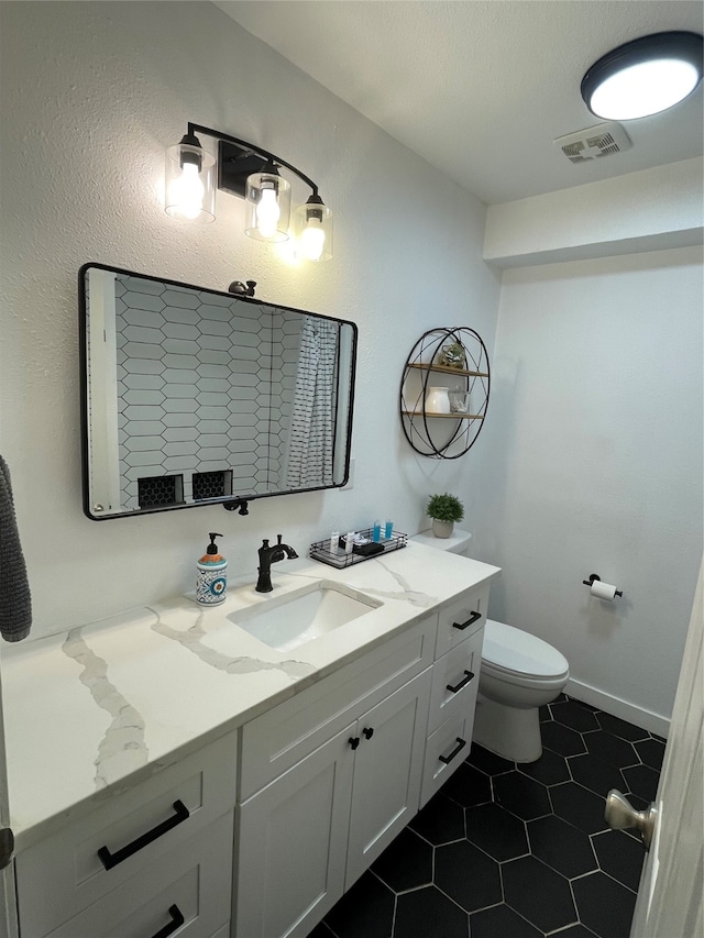 bathroom with vanity, toilet, a textured ceiling, and tile patterned floors