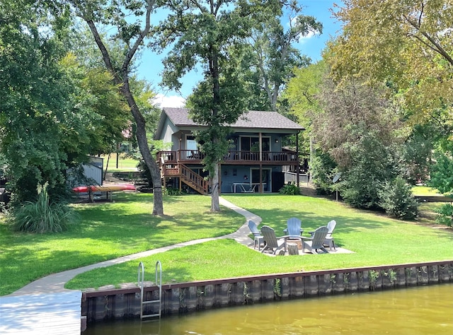 back of house with a yard, a deck with water view, and an outdoor fire pit