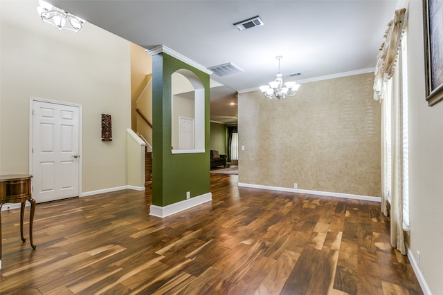 unfurnished dining area featuring dark hardwood / wood-style flooring, crown molding, and a chandelier