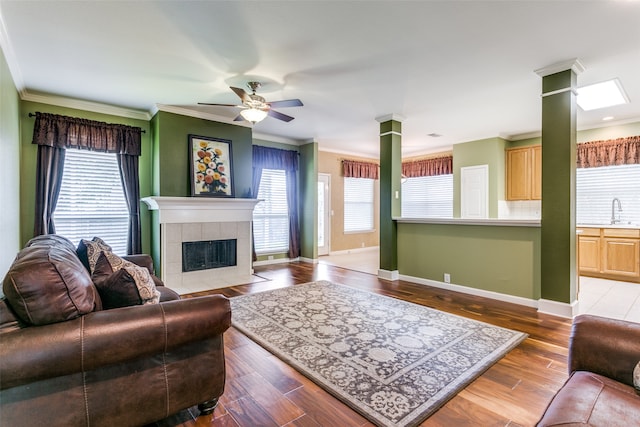 living room featuring plenty of natural light, wood-type flooring, and a tiled fireplace