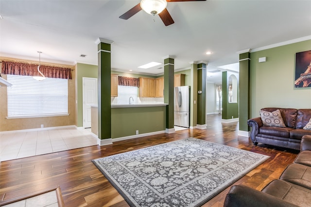 living room featuring ceiling fan, wood-type flooring, ornamental molding, and decorative columns