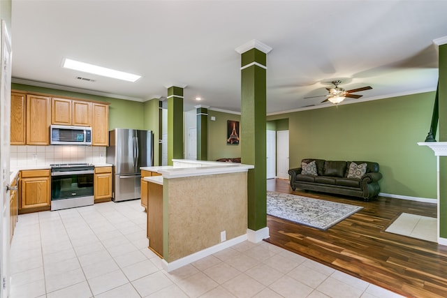 kitchen featuring ceiling fan, light hardwood / wood-style flooring, kitchen peninsula, appliances with stainless steel finishes, and ornamental molding