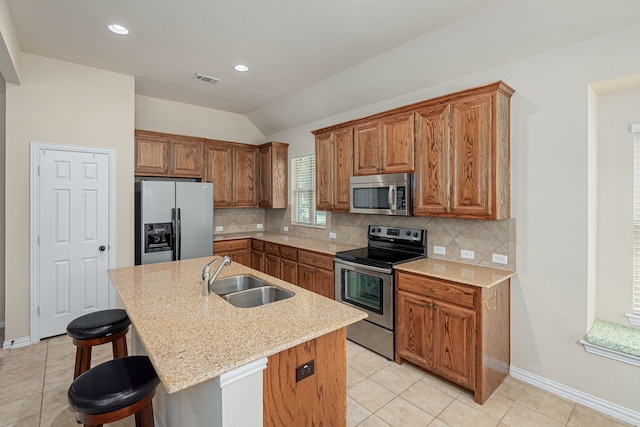 kitchen with a kitchen breakfast bar, a center island with sink, appliances with stainless steel finishes, decorative backsplash, and sink