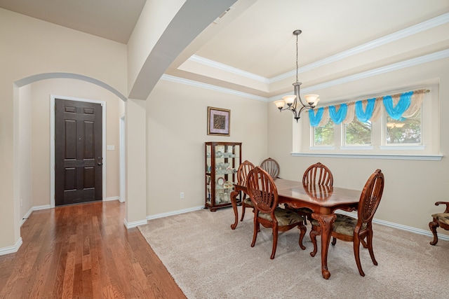 dining space with a tray ceiling, an inviting chandelier, crown molding, and wood-type flooring