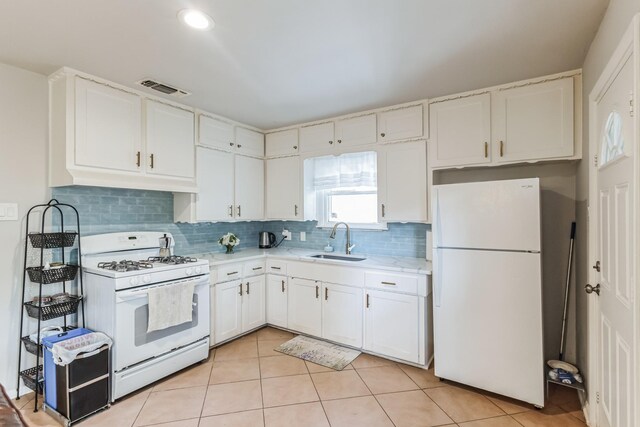 kitchen with decorative backsplash, white cabinetry, sink, light tile patterned floors, and white appliances