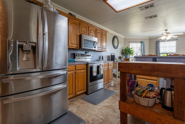 kitchen featuring ceiling fan, ornamental molding, a textured ceiling, and appliances with stainless steel finishes