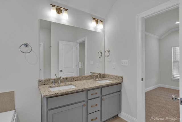 bathroom with dual bowl vanity, vaulted ceiling, and crown molding