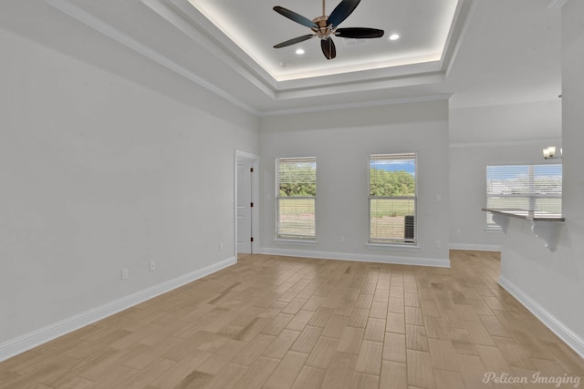 unfurnished living room featuring ceiling fan, a raised ceiling, and light wood-type flooring