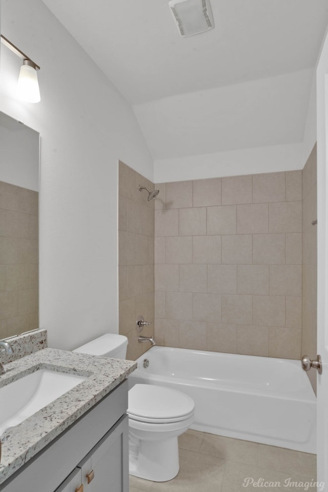 full bathroom with vanity, tiled shower / bath combo, lofted ceiling, and toilet