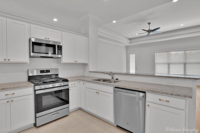 kitchen with stainless steel appliances, ceiling fan, a tray ceiling, white cabinetry, and kitchen peninsula