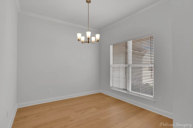 spare room featuring a notable chandelier, light wood-type flooring, and crown molding