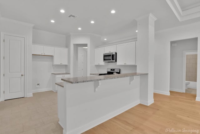 kitchen featuring crown molding, appliances with stainless steel finishes, light wood-type flooring, white cabinetry, and kitchen peninsula