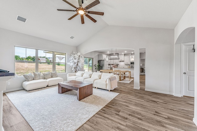 living room with wood-type flooring, high vaulted ceiling, and ceiling fan