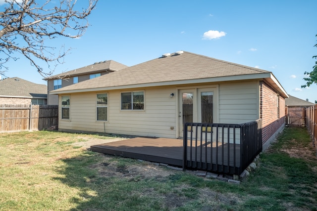 rear view of property featuring a wooden deck and a lawn