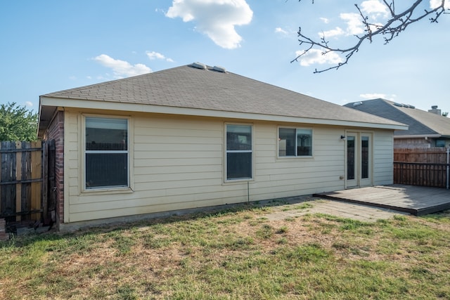 rear view of property with a wooden deck and a lawn