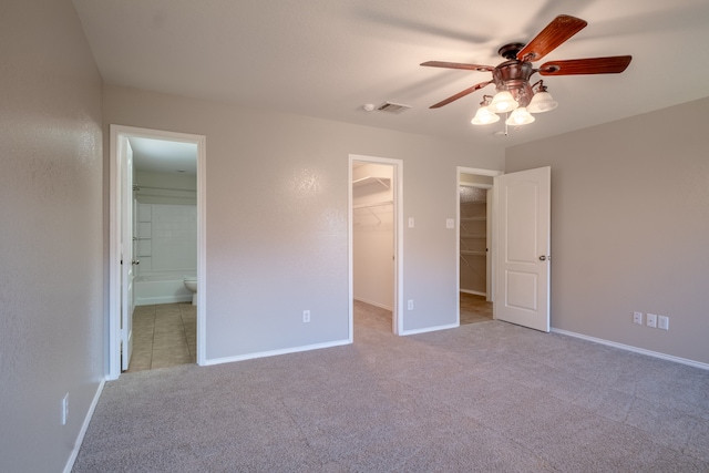 unfurnished bedroom with ceiling fan, carpet floors, a closet, ensuite bathroom, and a walk in closet