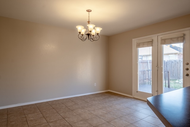 tiled spare room featuring a notable chandelier