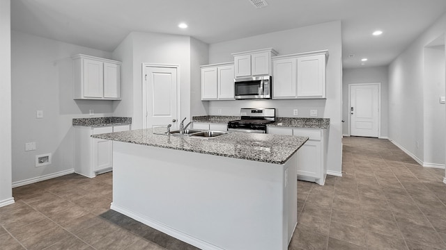 kitchen with appliances with stainless steel finishes, light tile patterned flooring, white cabinets, and sink