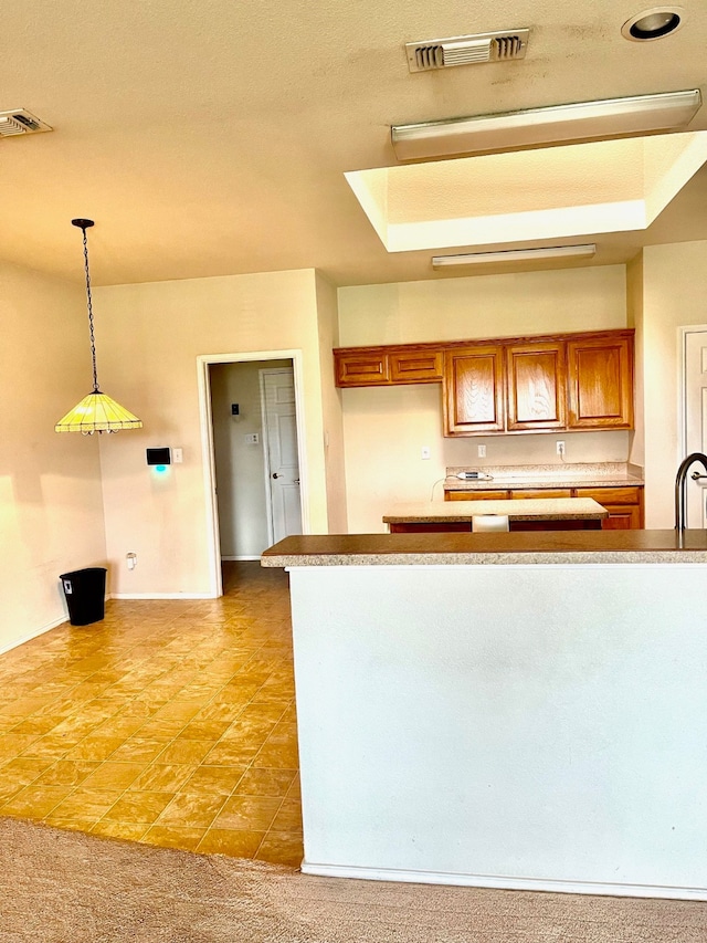 kitchen with a tray ceiling, hanging light fixtures, and carpet floors