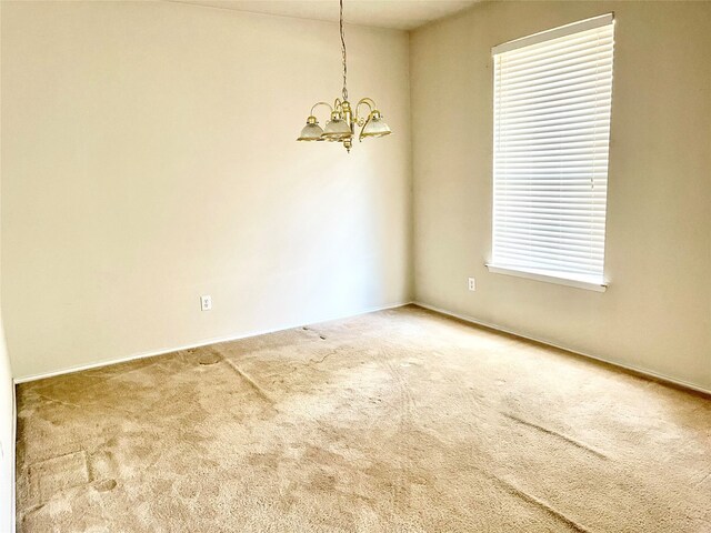 unfurnished room featuring carpet and a notable chandelier