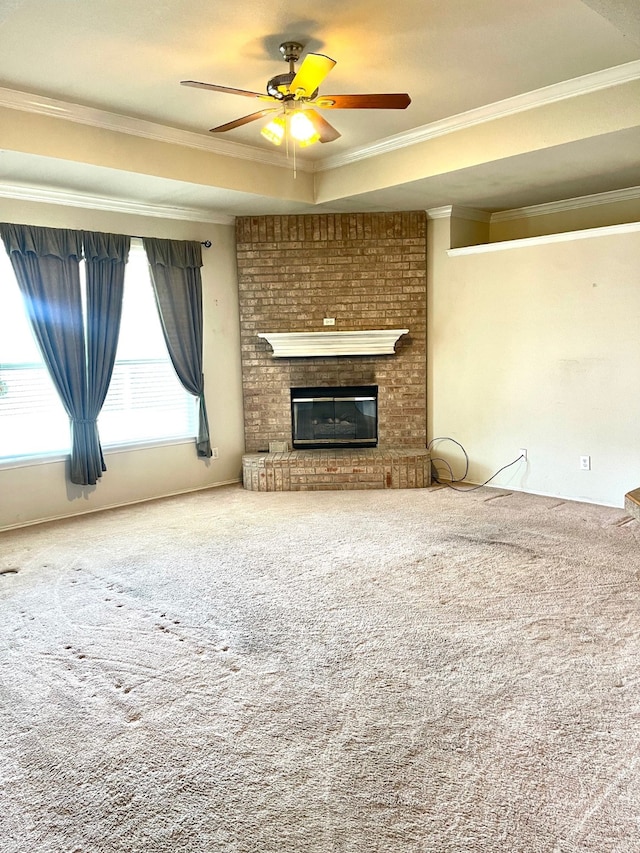 unfurnished living room with carpet flooring, ceiling fan, ornamental molding, and a brick fireplace