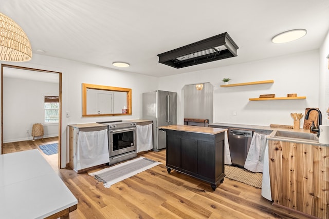 kitchen with appliances with stainless steel finishes, light wood-type flooring, sink, and a center island