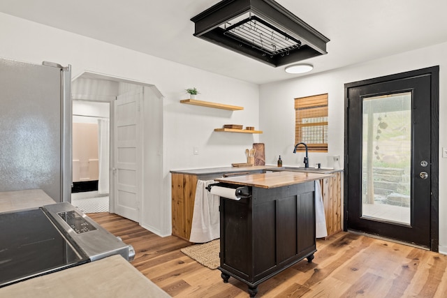 kitchen featuring stainless steel fridge, stove, sink, and light hardwood / wood-style floors