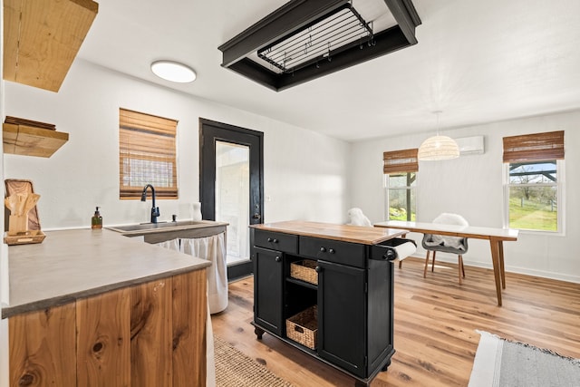 kitchen featuring light hardwood / wood-style flooring, kitchen peninsula, butcher block countertops, hanging light fixtures, and sink