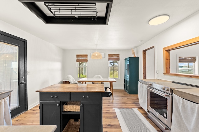 kitchen with light wood-type flooring, stainless steel electric range, and hanging light fixtures