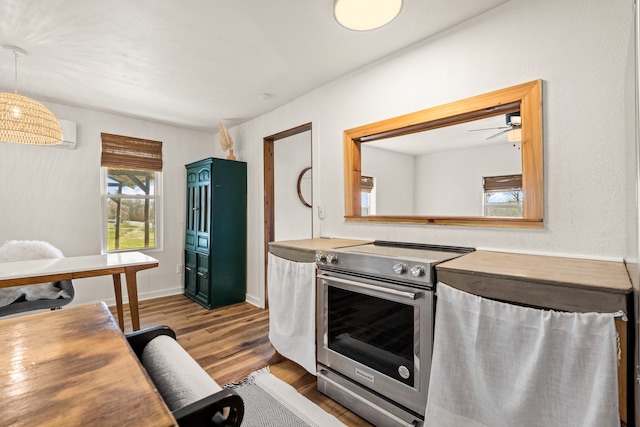 kitchen with ceiling fan, stainless steel range with electric stovetop, light wood-type flooring, and hanging light fixtures