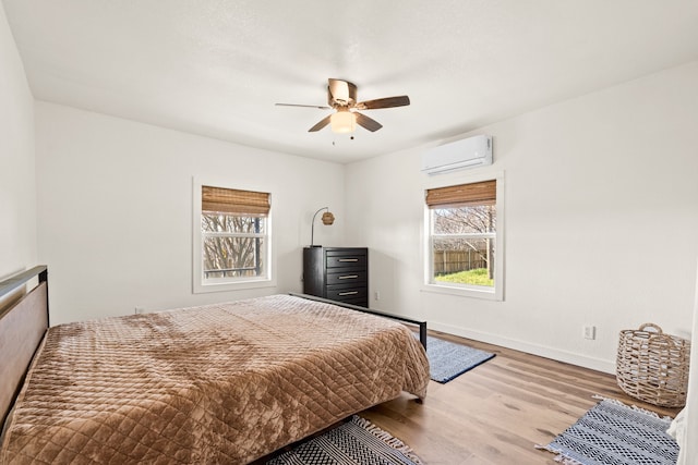 bedroom with ceiling fan, hardwood / wood-style floors, and a wall mounted air conditioner