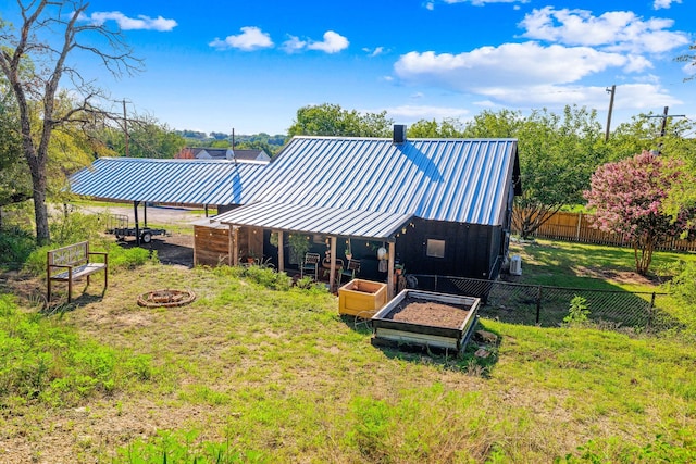 back of house featuring a lawn, an outdoor fire pit, and an outdoor structure